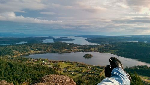 Low section of man standing on mountain against sky