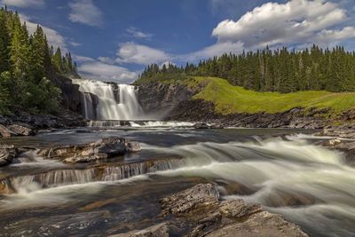 Scenic view of waterfall against sky