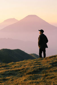 Full length of man standing on field against sky during sunset