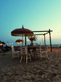 Chairs and tables at beach against clear sky