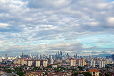 View of cityscape against cloudy sky