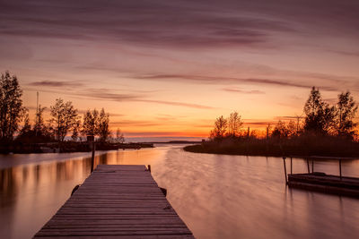 Pier in sea at sunset