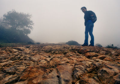 Low angle view portrait of woman standing on rocks against sky