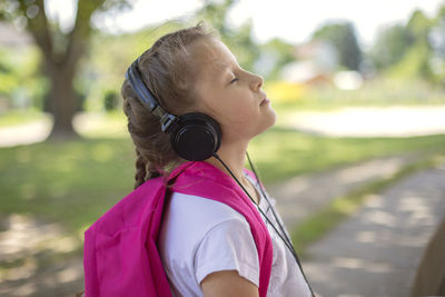 Close-up of a happy girl in black headphones. relaxing children in nature. rest from study