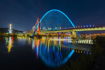 Illuminated bridge over river at night