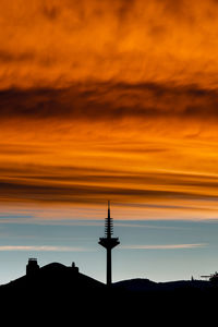 Low angle view of silhouette buildings against orange sky