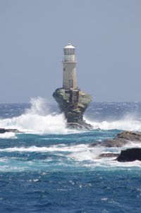 Lighthouse by sea against clear sky