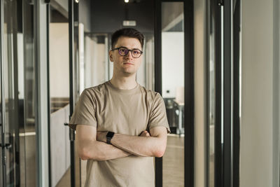 Portrait of young man standing against wall