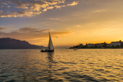 Sailboat sailing on sea against sky during sunset