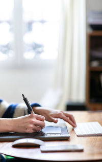 Midsection of man using mobile phone on table