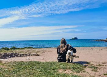 Man sitting on bicycle at beach against sky