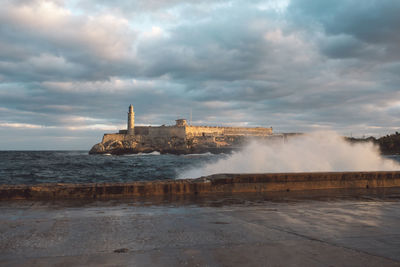 Scenic view of sea and buildings against cloudy sky