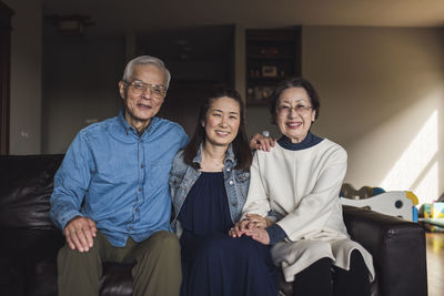 Portrait of adult daughter and her senior parents in living room