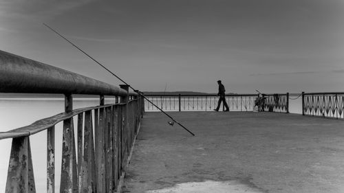 Man standing on pier over sea against sky