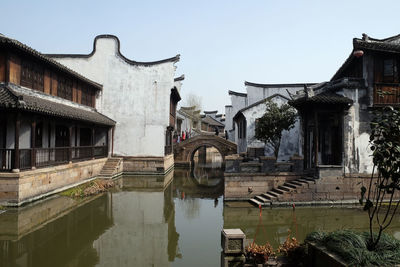 Reflection of buildings in canal against clear sky