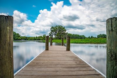 Wooden pier on lake against sky