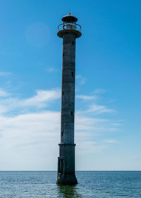 Lighthouse by sea against sky