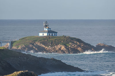 Lighthouse by sea against clear sky