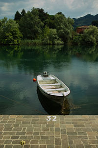 Boat moored on lake against sky