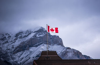 Low angle view of flag on snowcapped mountain against sky