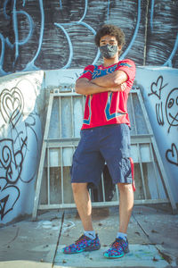 Portrait of man wearing sunglasses standing against graffiti wall