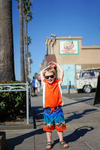 Portrait of smiling boy wearing sunglasses on footpath