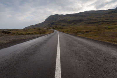 Empty road by mountain against sky