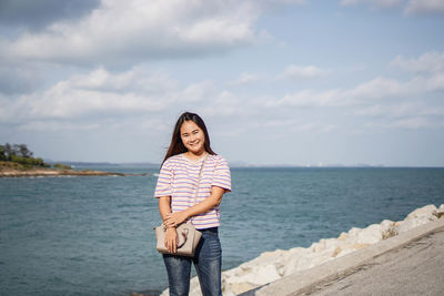 Portrait of smiling woman standing on sea against sky