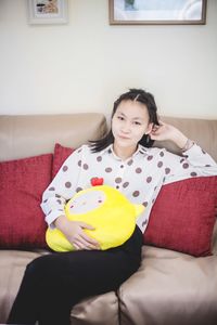 Portrait of girl sitting on sofa at home