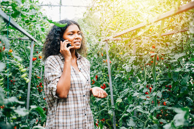 Young woman looking away while standing against plants