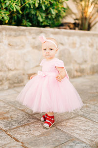 Portrait of cute girl with pink dress standing outdoors