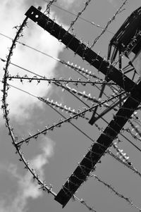 Low angle view of power lines against cloudy sky