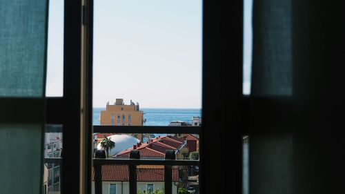 Cityscape by sea against clear sky seen through window
