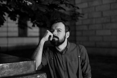 Young man smoking against wall