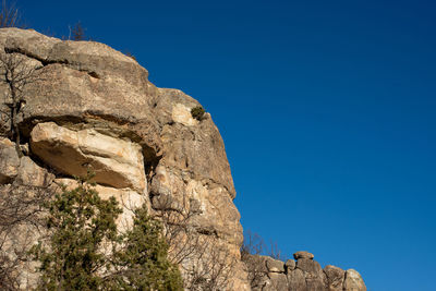 Low angle view of rock formation on clear blue sky