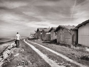 Rear view of man walking on field against sky