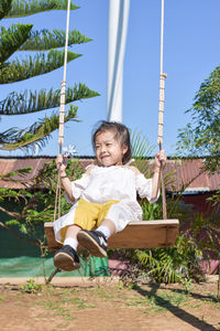 Happy girl sitting on plant against sky