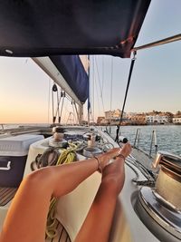 Midsection of woman sailing on sea against sky during sunset