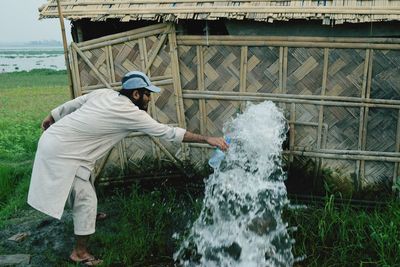 Man filling bottle from splashing fountain