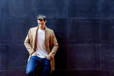 Young man standing against wall