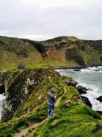 Rear view of woman standing on mountain by sea