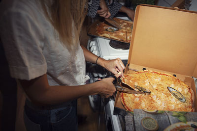 Woman cutting pizza with scissors