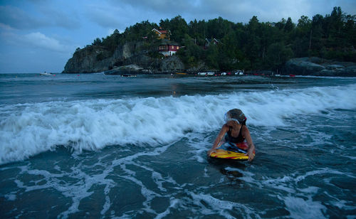 Girl surfing in sea at dusk