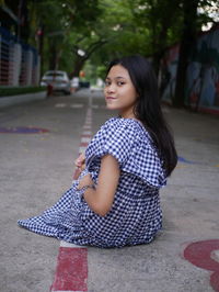 Portrait of young woman standing against trees