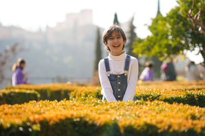 Portrait of girl laughing while standing amidst plants