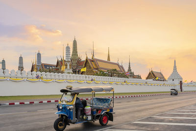 Grand palace and wat phra keaw at sunset bangkok, thailand. blue tuk tuk, thai traditional taxi