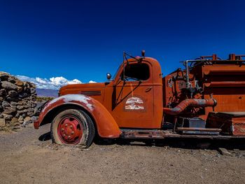 Abandoned truck on field against clear blue sky