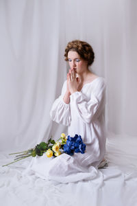 Portrait of young woman sitting on bed at home