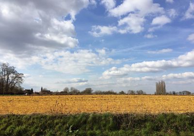 Scenic view of field against cloudy sky