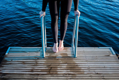 Woman's feet standing on steps down to cold water for swimming